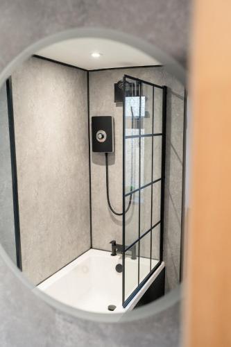 a shower in a bathroom with a mirror at Stunning 2 Bedroom Beach Apartment With Garden in Rhos-on-Sea