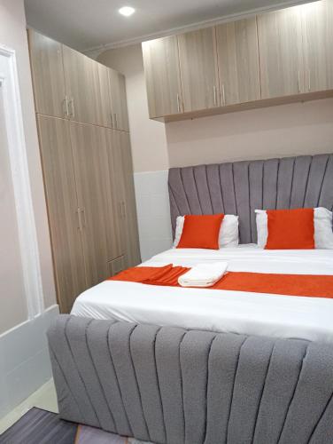 a bedroom with a large bed with two orange pillows at Lora's Haven Homes, Nakuru - 1 Bedroom in Nakuru