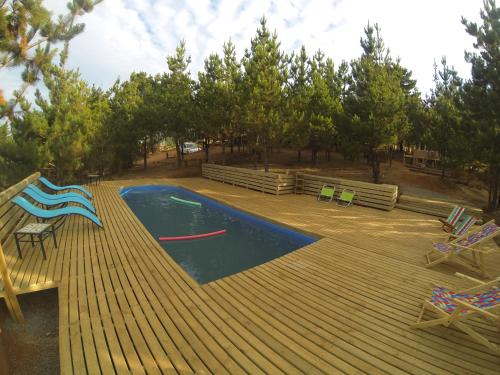 a swimming pool with a deck and chairs and trees at Cabañas & SPA Carilafquen in Laguna Verde