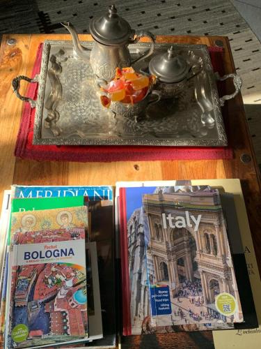 a table with a tray with a tea pot and books at B&B Marana 14 Casa di Campagna in Bologna