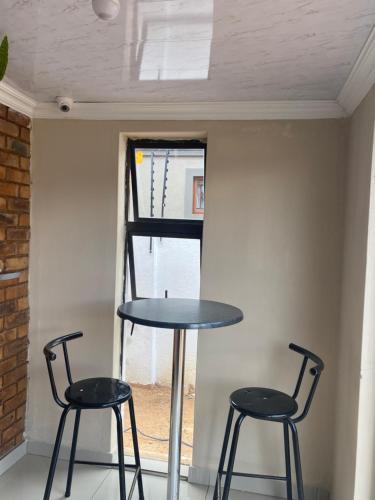 two chairs and a table in front of a window at Maoba GuestHouse in Soshanguve