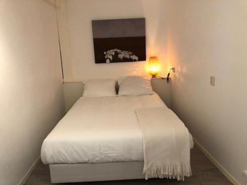 Cama blanca en un dormitorio pequeño con lámpara en BY BABS guesthouse Bergen nh, en Bergen