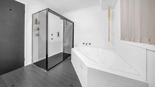 a white bathroom with a shower and a bath tub at Blue Willow Bathurst Country Getaway in Bathurst