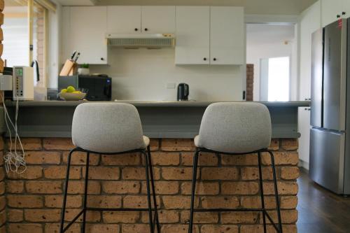 a kitchen with two chairs in front of a brick wall at Blue Willow Bathurst Country Getaway in Bathurst