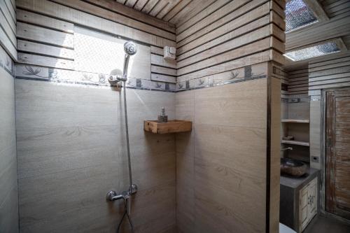 a shower in a bathroom with wooden walls at Uma Caming Villa Ubud in Tegalalang
