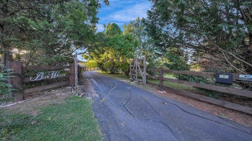 a wooden fence with a road next to a gate at Blue Willow Bathurst Country Getaway in Bathurst
