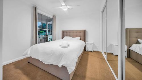 Un dormitorio con una gran cama blanca y un espejo. en Blue Willow Cottage - Bathurst, en Bathurst