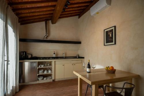 a kitchen with a wooden table and a table with a bottle of wine at Tenuta San Jacopo - Agriturismo in Cavriglia