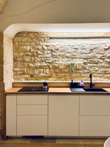 a kitchen with two sinks and a stone wall at Il Magazzeno della Prozia in Corato