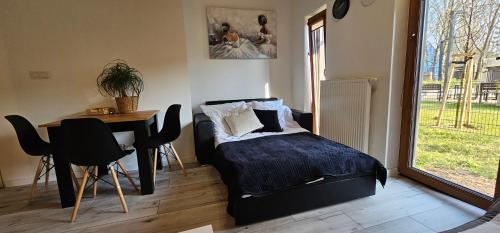 a bedroom with a bed and a table and a window at Apartament Vip - Studio - Silverforest 69 in Szczecin