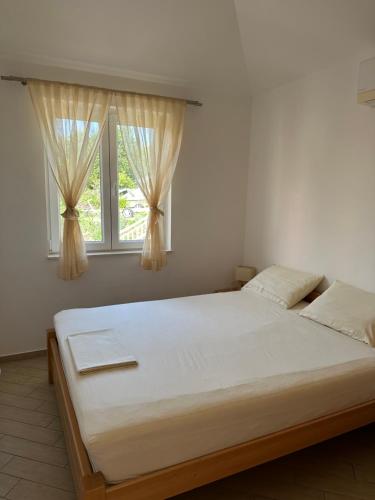 a large bed in a room with two windows at Apartments Villa Eva in Slano