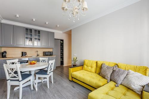 a living room with a yellow couch and a table at Elegant Apartment in Rīga