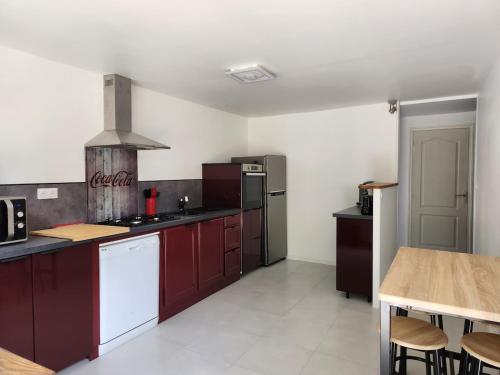 une cuisine avec des appareils rouges et blancs et une table dans l'établissement La Ferme Saint Jean, à Pontorson