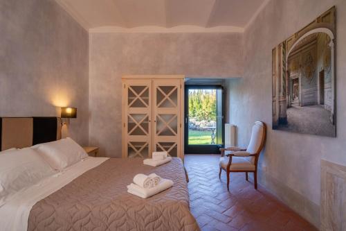 a bedroom with a bed and a chair and a window at Tenuta San Jacopo - Agriturismo in Cavriglia