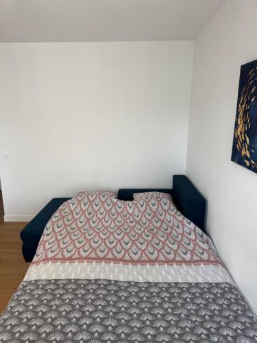 a bed with a quilt on it in a room at Le 9 - Basel Airport in Saint-Louis