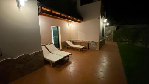 a patio with two white chairs and a stone wall at Villa Sofia in Marina di Campo