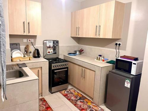 Una pequeña cocina con estufa y microondas. en Romish Luxury Homes, en Nairobi