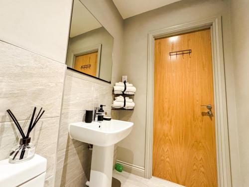 a bathroom with a sink and a mirror and a toilet at Prime Leeds- Spacious Cinema apartment in Central Station