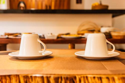 two cups sitting on top of a wooden table at Morena Jambo in Arraial d'Ajuda