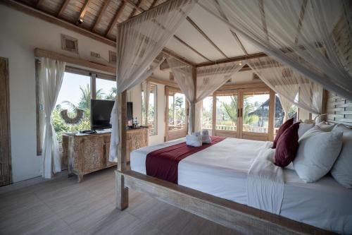 a bedroom with a canopy bed and a television at Uma Caming Villa Ubud in Tegalalang