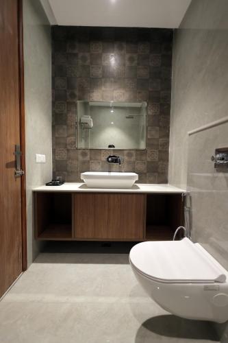 a bathroom with a sink and a toilet and a mirror at Hotel Regal Palm in Morādābād