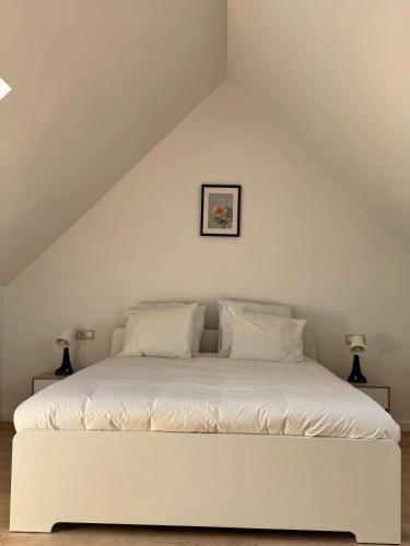 a white bed with white pillows in a attic at Loft Luna Brussels Midi in Brussels