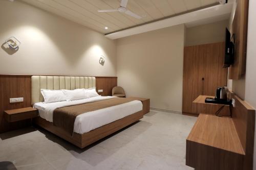 a hotel room with a bed and a table and a tv at Hotel Regal Palm in Morādābād