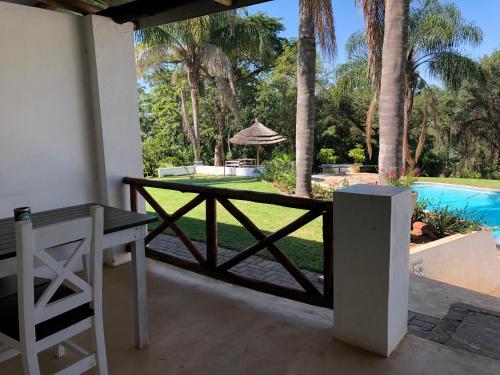 a patio with a table and a pool and palm trees at Georges Valley Lodge in Tzaneen