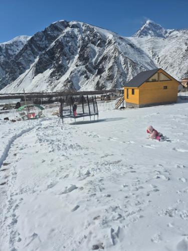 a person laying in the snow in front of a cabin at mood villa kazbegi in Stepantsminda