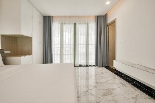 a bedroom with a large white bed and large windows at La isla Apartments & Villas - Sea View & Fireworks Phu Quoc in Phu Quoc