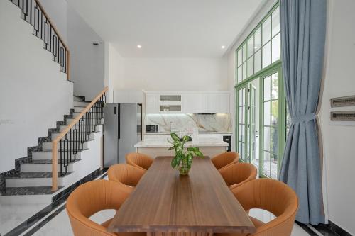 a dining room with a wooden table and orange chairs at La isla Apartments & Villas - Sea View & Fireworks Phu Quoc in Phu Quoc