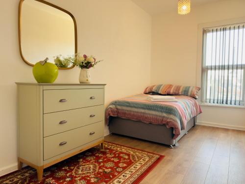 a bedroom with a bed and a dresser with a mirror at Lovely 2 bed Apartment, Arnold Town centre. in Nottingham