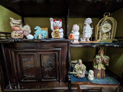 a shelf with various figurines and a clock on it at Villa Hachiman-gai ヴィラ八幡街 in Omihachiman