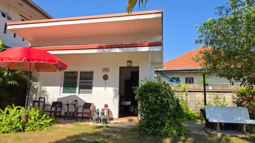 ein Haus mit einem roten Regenschirm, einem Tisch und Stühlen in der Unterkunft Smile house 354 in Chiang Rai