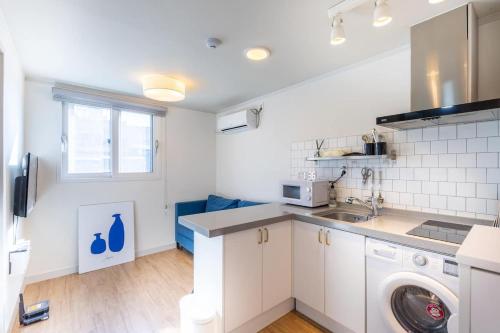 a white kitchen with a washer and dryer at Modern house across from Sinsa Garosu-gil, internet TV, parking available in Seoul