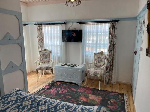 a bedroom with a bed and two chairs and a television at Mystic Konak in Selcuk