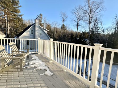 a wooden deck with two chairs and snow on it at 2 BR Home in Bar Harbor Town Hill "Deer Run" in Bar Harbor