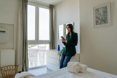 a woman standing in a bedroom looking at her phone at Yourbanflat Eremitani in Padova