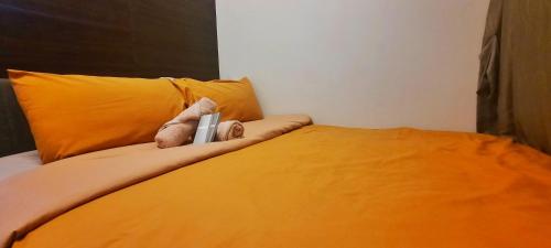 a bed with orange pillows and a stuffed animal on it at Air Residences-Stylish&Comfort Stay High flat with balcony in Manila