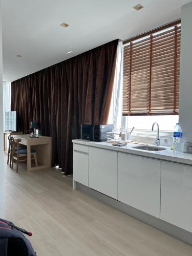 a kitchen with white cabinets and a table and a window at The beach front Condo in Ban Saiyuan (1)