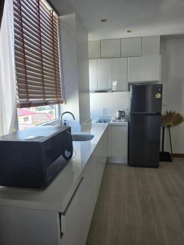 a kitchen with a microwave on a counter with a refrigerator at The beach front Condo in Ban Saiyuan (1)