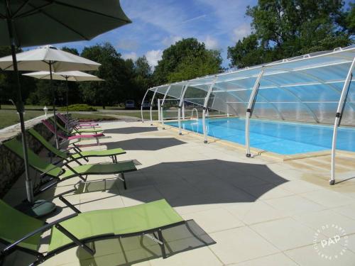 - une piscine avec des chaises et des parasols à côté d'un bâtiment dans l'établissement Mas d'Ambayrac chambres d'hôte Le four a pain, à Promilhanes