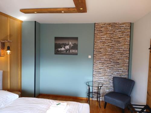 a bedroom with a bed and a chair and a brick wall at Pension & Apartments Weissbriach in Weissbriach