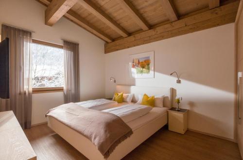 a bedroom with a large white bed with yellow pillows at Resort Tirol am Wildenbach in Niederau