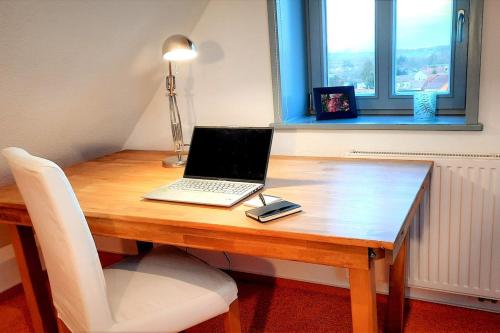 a laptop computer sitting on a wooden desk with a window at Ruhige Maisonette-Wohnung mit Blick über Röbel "Kleines Himmelreich" in Röbel