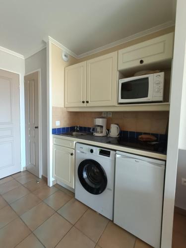une cuisine avec un lave-linge et un micro-ondes dans l'établissement Jolie appartement PIERRE & VACANCES avec vue sur mer St TROPEZ, à Grimaud