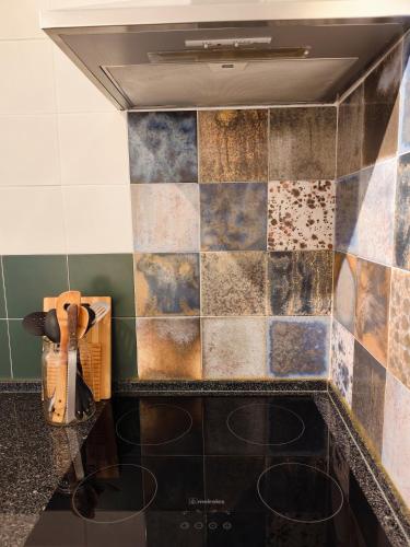 a kitchen with a tiled wall and a stove at Stressfree Apartamento in Vila Nova de Milfontes