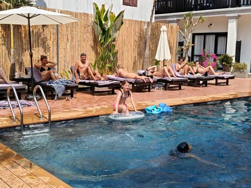 a group of people sitting around a swimming pool at Luang Prabang Vang Luang Hotel in Luang Prabang