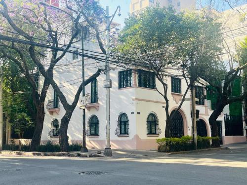 a white building with trees in front of a street at Hotel Casa Ensenada Luxury Boutique Hotel in Mexico City