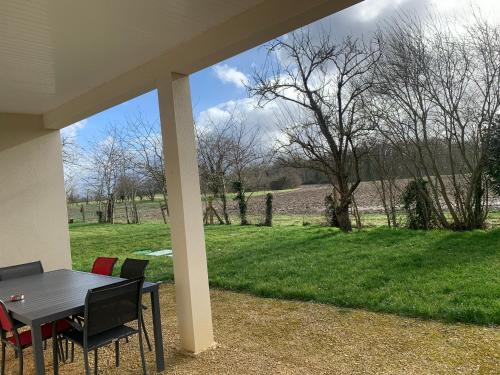 a table and chairs with a view of a field at Gîte neuf, à 12mn du Futuroscope, à la campagne-Le Coquelicot in Saint-Léger